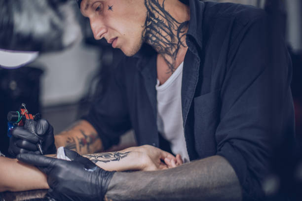 istock Artist drawing tattoo on woman's hand in studio 920648418