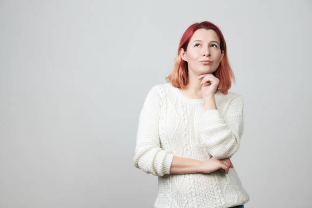 istock Thoughtful girl in white sweater holding hand under her head 920681476