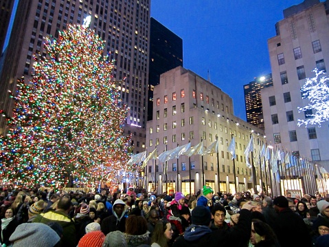 Colorful Rockefeller Center Christmas Tree at night surrounded by holiday crowds and illuminated buildings