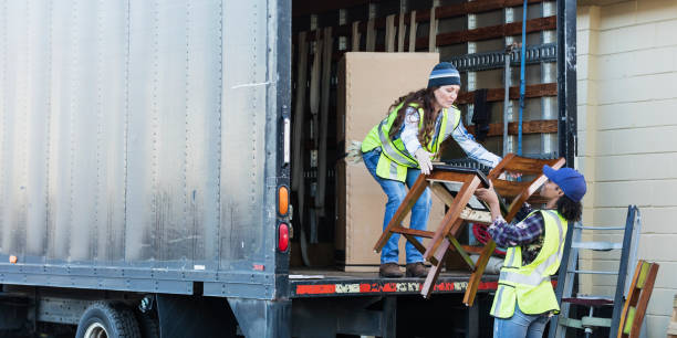 due lavoratrici con un camion, mobili mobili in movimento - moving van truck loading delivery person foto e immagini stock