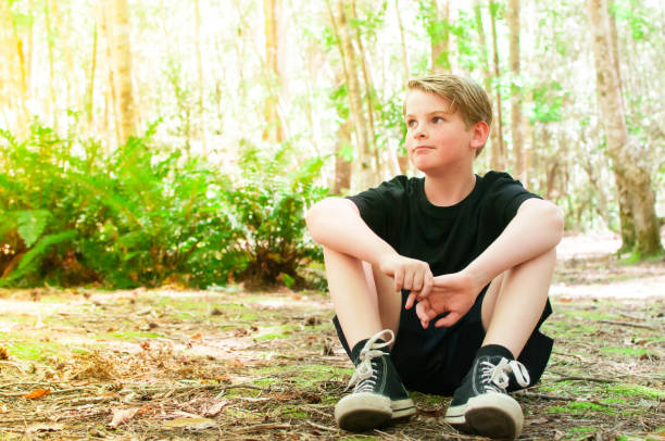 child casually sitting on forest floor in tasmania, australia - healthy lifestyle nature sports shoe childhood imagens e fotografias de stock