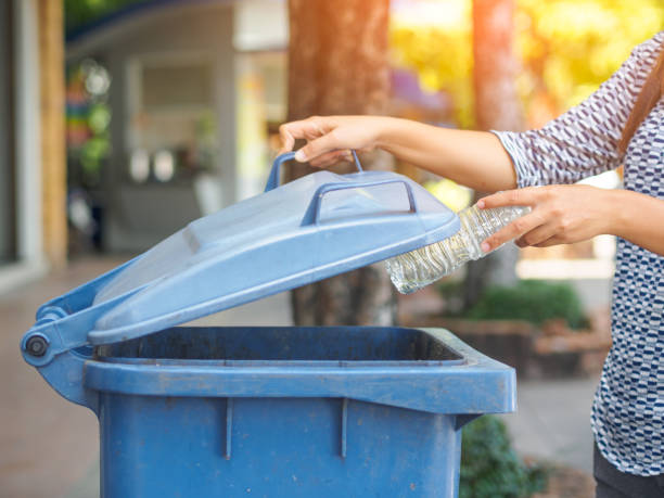 istock Closeup portrait woman hand throwing empty plastic water bottle in recycling bin. 920717810