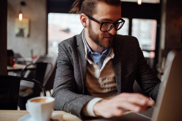 istock Young bearded businessman looking at laptop while sitting in a cafe 920720512