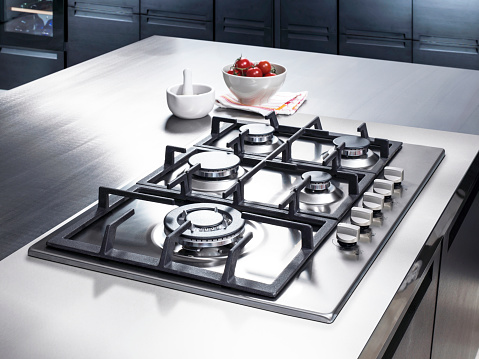 Flat cooktop cooking induction electric built black stove. Grey beige countertop with black glossy built in ceramic tempered glass induction or electric hob stove cooker with four burners, in kitchen.