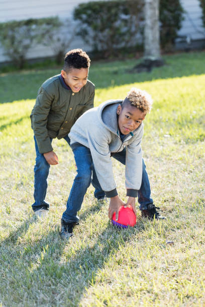 istock Two boys playing football in back yard 920735936