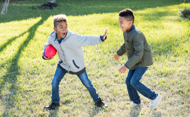 istock Two boys playing football in back yard 920738316