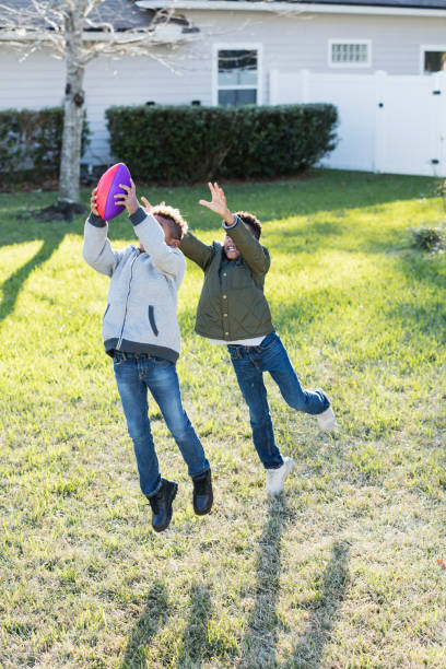 istock Two boys playing football in back yard 920738380