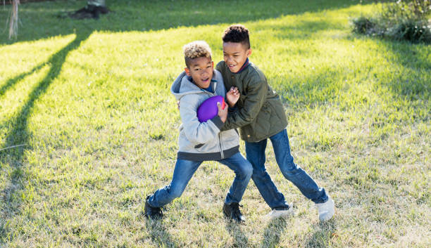 istock Two boys playing football in back yard 920738382