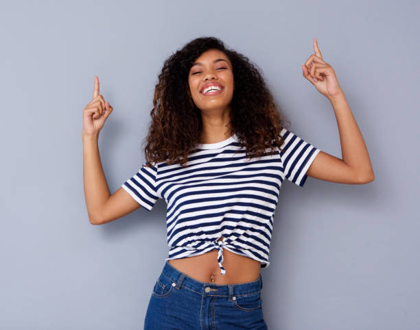 istock happy young black woman smiling and pointing up 920743372