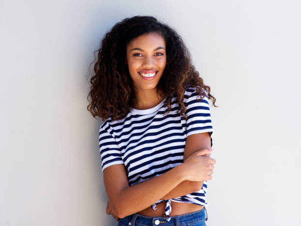 istock confident young black woman smiling against white wall 920743436
