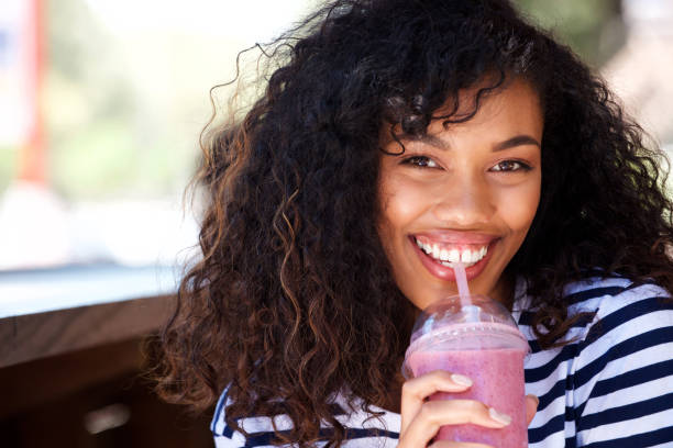 istock Close up beautiful young woman drinking smoothie 920743500