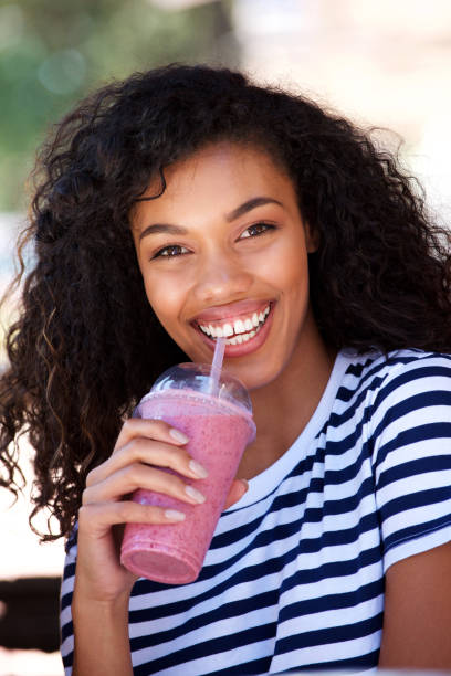 istock smiling young woman drinking smoothie outside 920743502