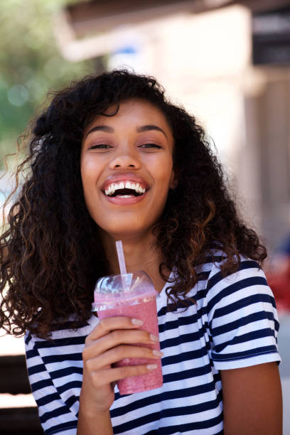 istock Young woman laughing with smoothie drink 920743504