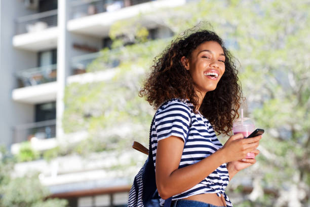 istock happy young african woman walking outdoors with cellphone 920743524