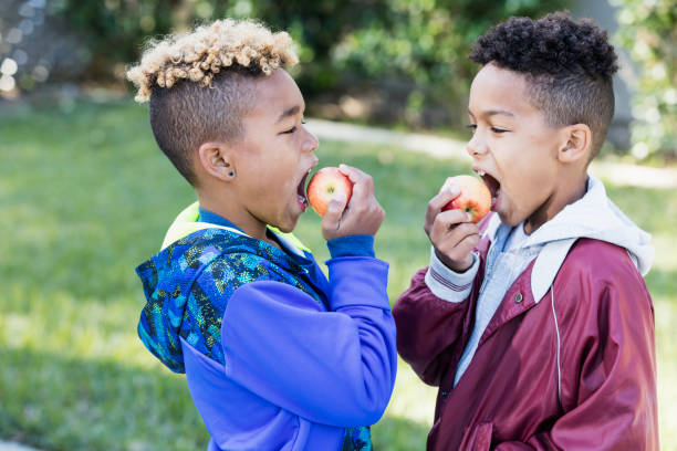 dos niños comer manzanas - apple healthy eating eating black fotografías e imágenes de stock