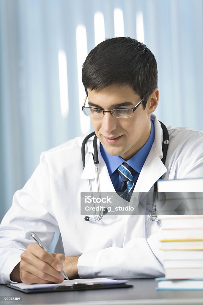Szczęśliwy Młody lekarz lub student piśmie w biurze - Zbiór zdjęć royalty-free (Badanie lekarskie)