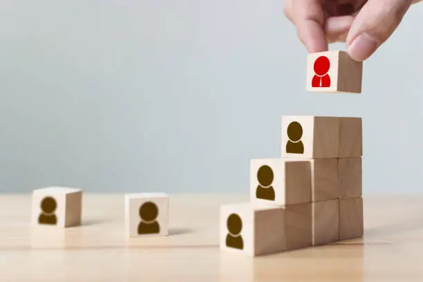 Photo of Human resources and talent management and recruitment business concept, Hand putting wood cube block on top staircase, Copy space