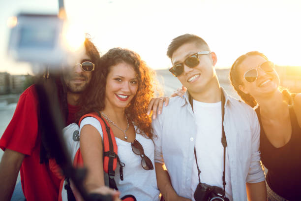 istock Happy young people taking selfies with selfie stick in city. 920777906