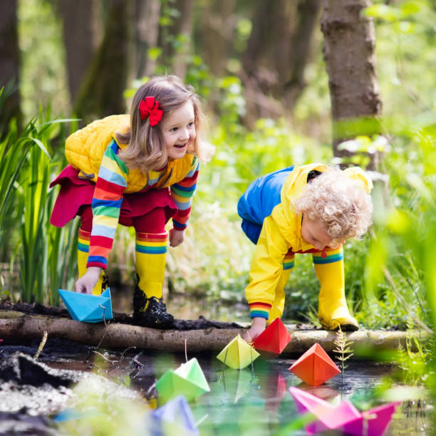 bambini che giocano con barche di carta colorate in un parco - 11242 foto e immagini stock