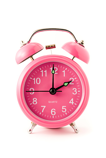 Pink clock isolated on white showing 12 O'clock.