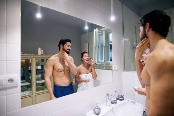 istock Muscular shirtless man checking beard while standing with an adorable girlfriend in front of a mirror in the bathroom. 920831226
