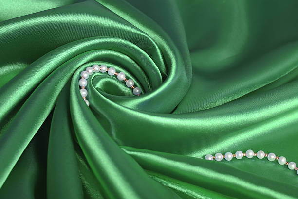 Pearl beads on green silk stock photo