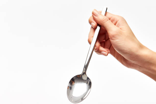 istock woman's right hand holds a spoon on a white background. 920844860
