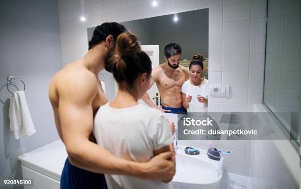 Young Curious Couple Standing Hugged In The Bathroom With A Pregnancy Test Waiting For The Results In Front Of The Mirror Stock Photo - Download Image Now