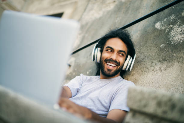 casual young hipster with dreadlocks listening music at street and looking aside. - multi tasking asian and indian ethnicities asian ethnicity lifestyles imagens e fotografias de stock