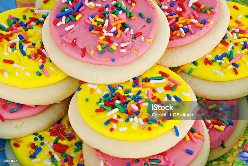 Homemade Sugar Cookies With Yellow and Pink Frosting and Sprinkles Homemade sugar cookies with a circular shape topped off with yellow and pink icing. Assorted color sprinkles are on the top of each cookie. This is a close up macro studio shot. Multi use colors can be used for Easter or springtime baking.  Cookie Stock Photo