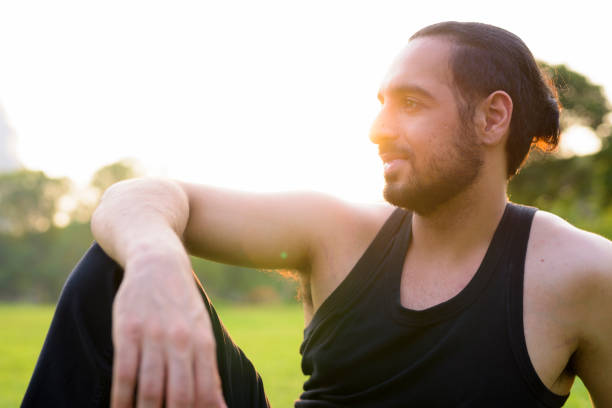 istock Young Indian Man In Park Sitting On Grass 920852596