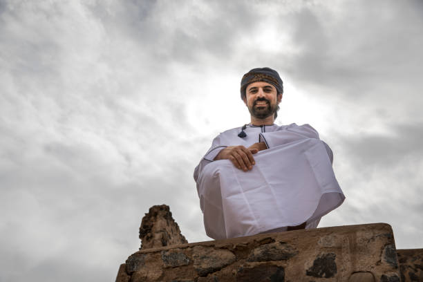 arab man in traditional omani outfit against a stormy sky stock photo