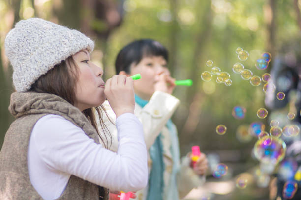 istock Happy Japanese sisters playing with bubbles in forest 920870622
