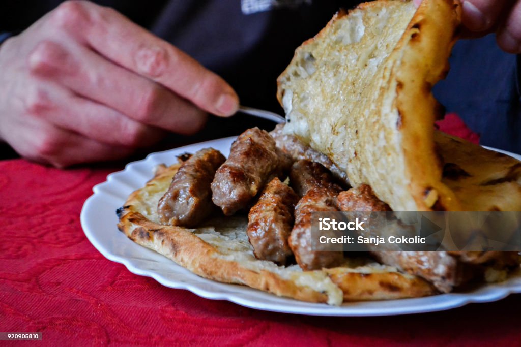 Traditional Bosnian and Balkans food, meat in bread, cevapi Closeup of traditional Balkan food- meat in bread/ man eating cevapi Food Stock Photo