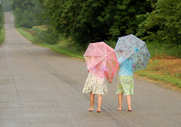 istock Two kids Walking Together Hand-in-Hand With Umbrellas 92090975