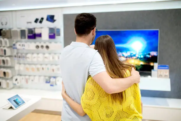 Photo of Happy couple in tech store, purchasing devices for their new home.