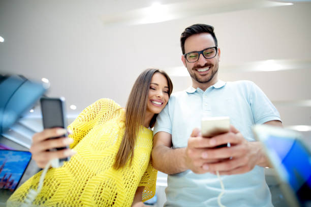 istock Happy couple buying new smart phone in tech store. Comparing models and specifications. Testing front camera and quality of the photos. 920914568