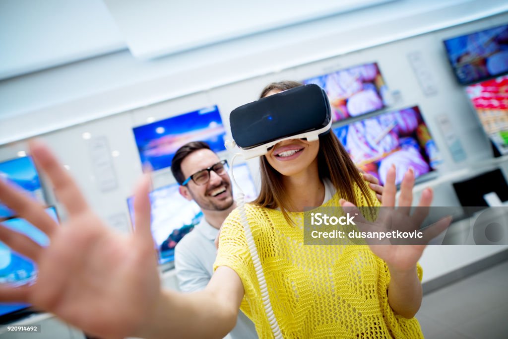 Couple in electronics store, exploring VR goggles. Retail Stock Photo