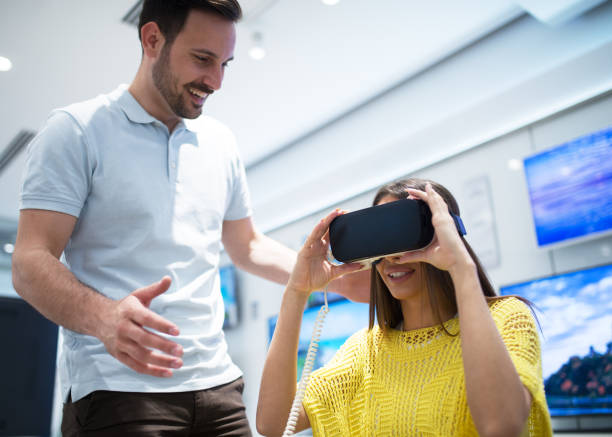 Couple in electronics store, exploring VR goggles looking for right one to buy.