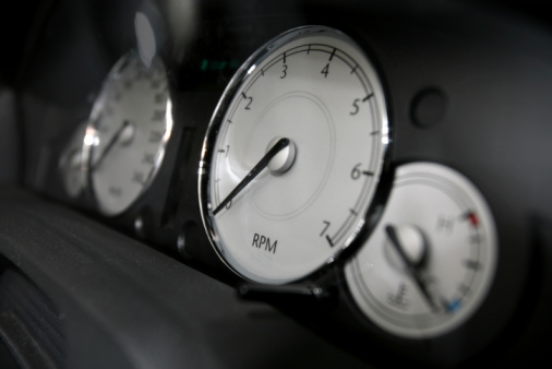 Car rev counter needle displays a rising engine speed.  Backlit display and needle.