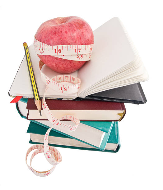 ビッグアップルに、完熟した測定テープ上の本の山 - book stack dieting textbook ストックフォトと画像