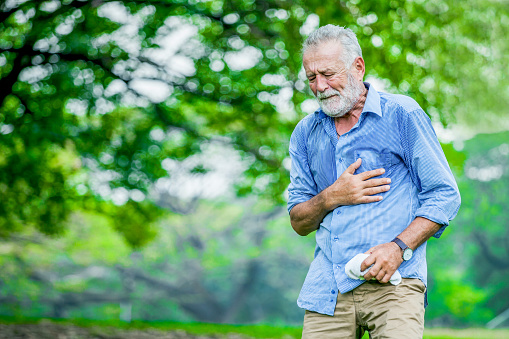 Heart attack concept. Senior man suffering from chest pain outdoor in park,