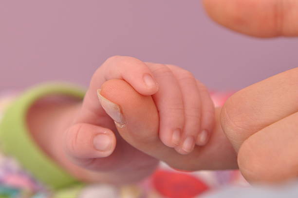 istock baby holding parents finger 92095086