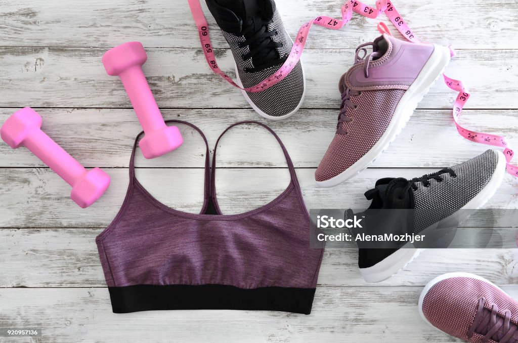 Ropa para mujer (sujetador de deporte), calzado (zapatillas) y aparatos (pesas color de rosa, cinta métrica). Concepto de estilo de vida activo, endecha plana - Foto de stock de Accesorio personal libre de derechos