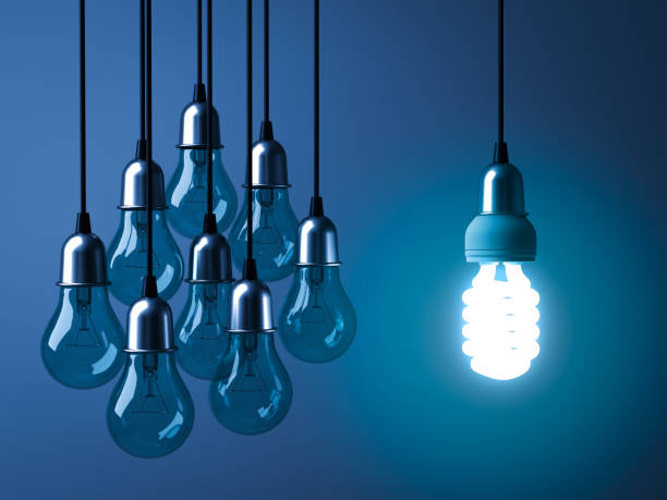 istock One hanging eco energy saving light bulb glowing and standing out from unlit incandescent bulbs on dark blue background 920957204