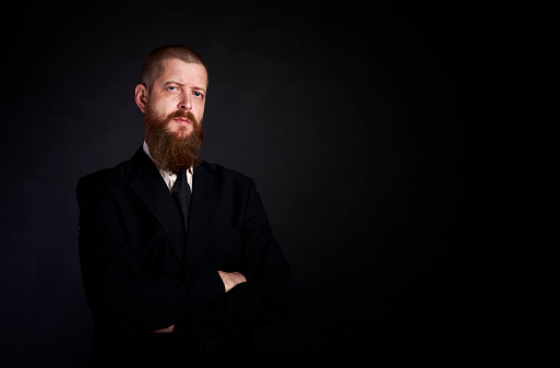 businessman with beard on black background in black suit