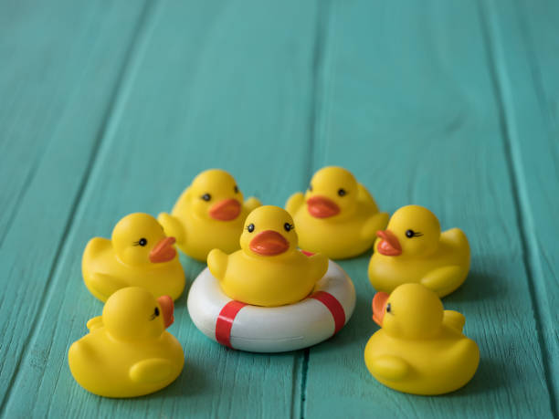 istock Group of yellow rubber ducks surrounding one that is sitting on a inflatable life ring. 920974816