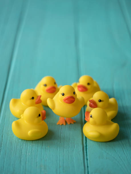 istock Group of yellow rubber ducks surrounding one that is standing on it's legs. 920974818