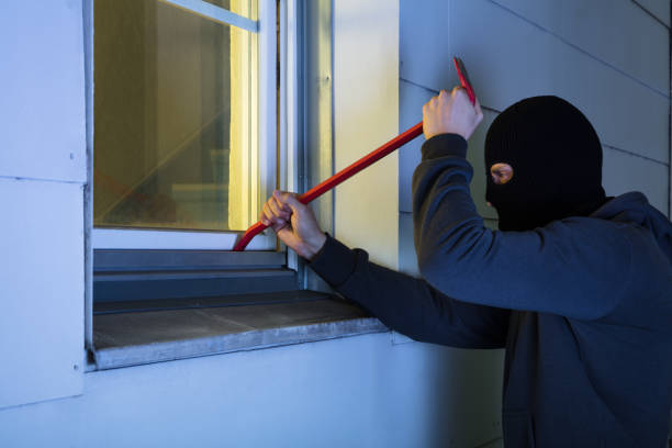 Burglar With Black Mask Using Crowbar To Break Into A House At Night