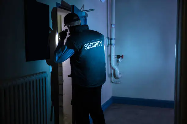 Photo of Rear View Of A Male Security Officer With Flashlight